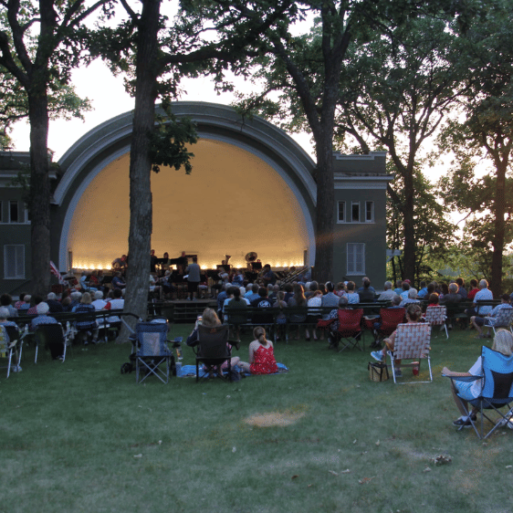 Fairmont City Band playing instruments at Sylvania Park with a crowd watching