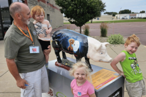 Family posing for picture in front of a going hog wild pig statue in Fairmont minnsota