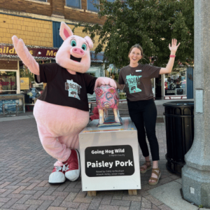 Marty the Pig from Bacon Capital and girl posing with a Going Hog Wild pig statue in Fairmont, Minnesota