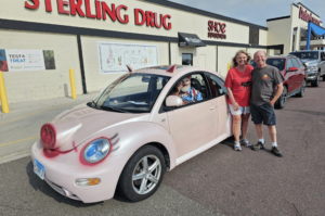 Couple posing in front of a car that looks like a pig in Fairmont, Minnesota