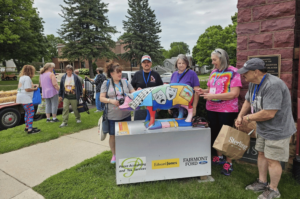 Happy Pig Collector members posting for picture in front of the Goild Hog Wild pig statue at Red Rock Center for the Arts in Fairmont, Minnesota