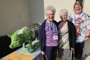 Happy Pig Collector ladies posting for picture in front of the Goild Hog Wild pig statue "Sterloin" in Fairmont, Minnesota