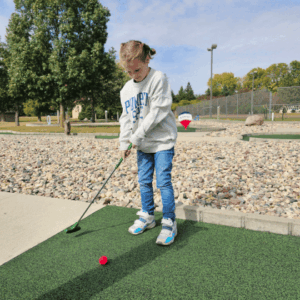 Kid playing on the free mini golf course in Fairmont, Minnesota